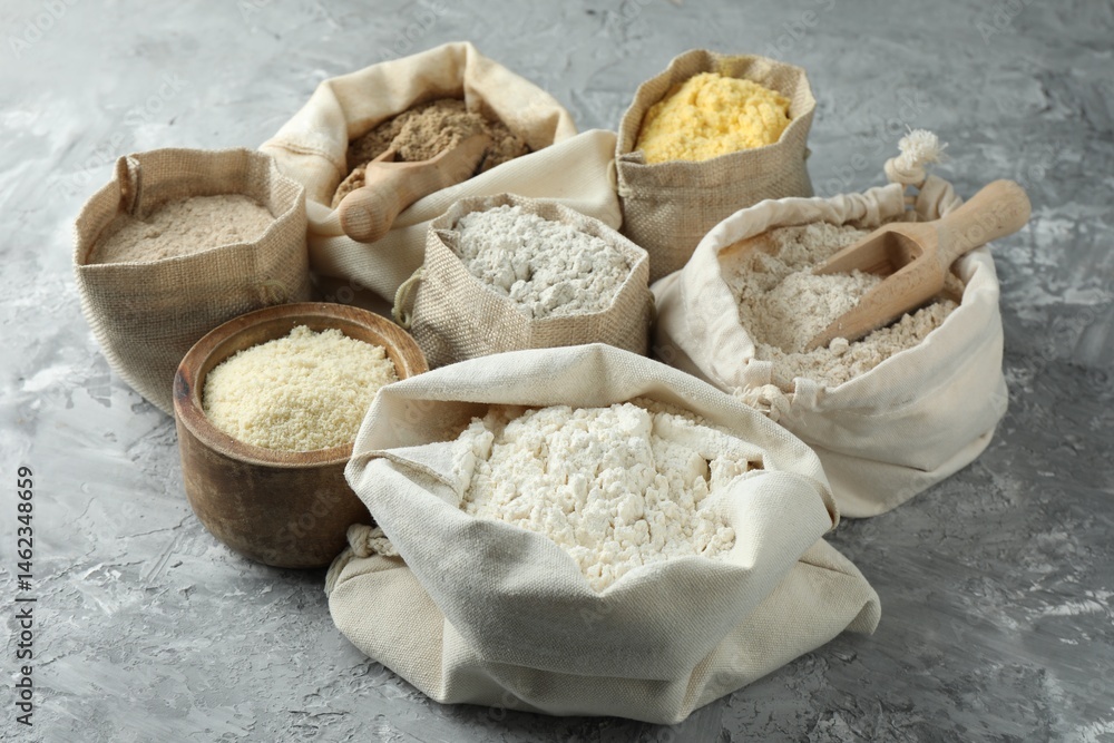 Fototapeta premium Different types of flour in bags on grey textured table, closeup