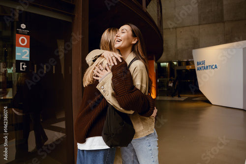 Принти на полотні Two female friends standing and hugging while one of them laughs
