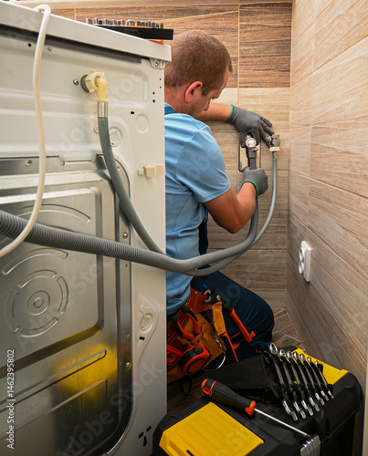 Professional plumber connecting water supply hose to washing machine in bathroom, ensuring proper installation and functionality