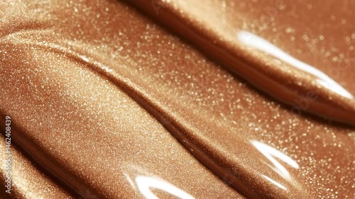 Golden metallic liquid texture with shimmering glitter and shiny bronze shimmer effect