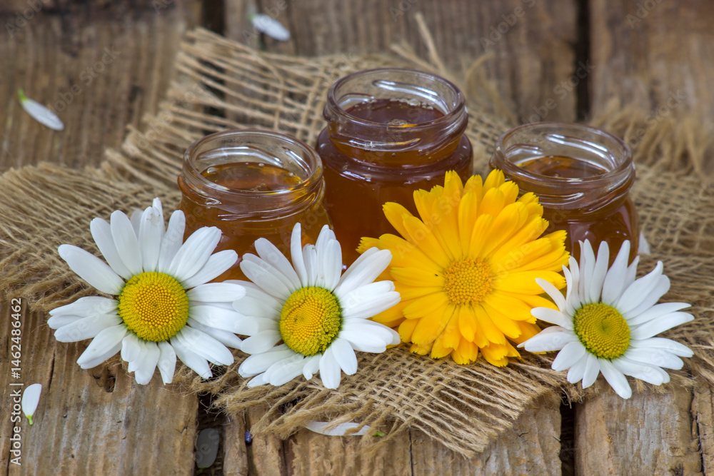 honey and flowers on wooden background