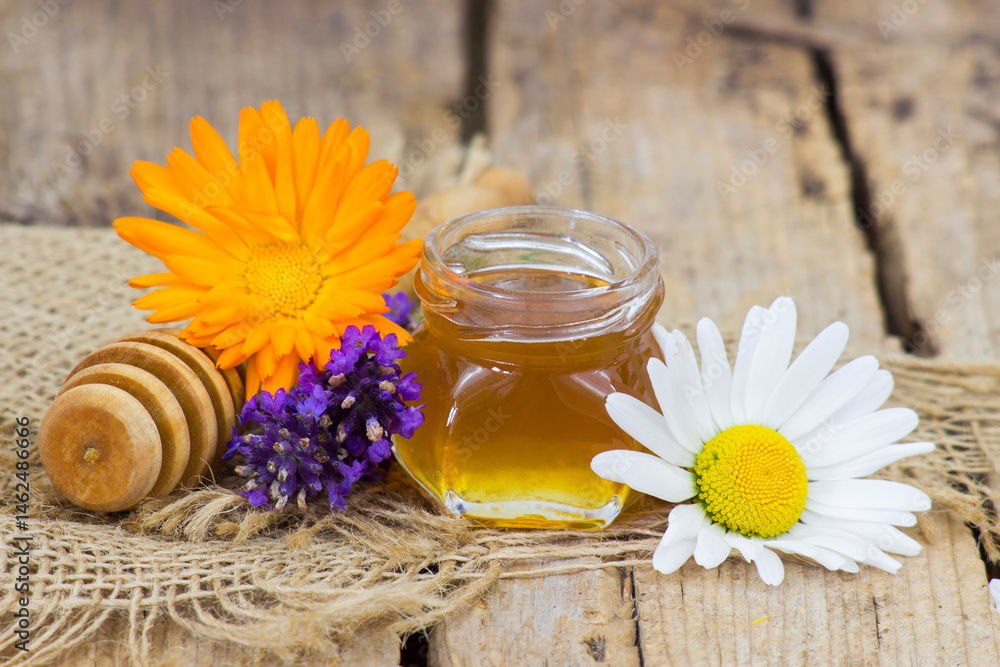 honey and flowers on wooden background