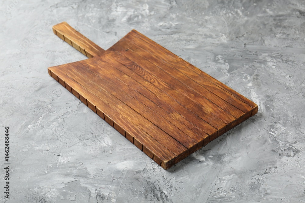 Fototapeta premium One wooden serving board on light grey textured table, closeup. Space for text