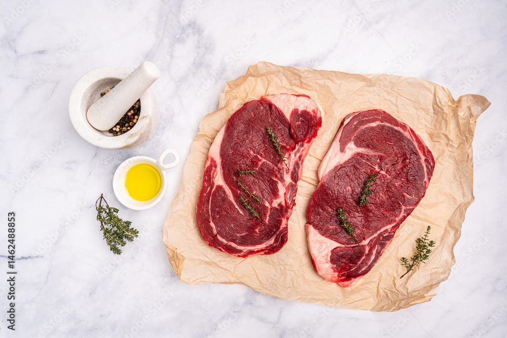 Raw fresh beef steak on a paper with spices on a white background. Top view with copy space. High quality photo