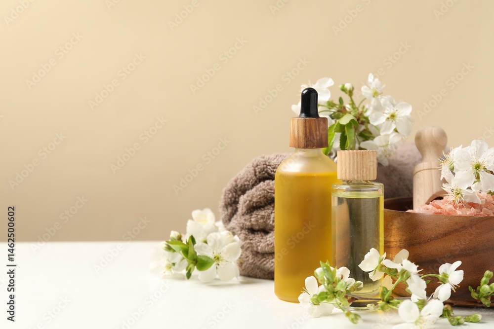 Spa composition with cosmetic products and beautiful flowers on white table against beige background, space for text Spa composition with cosmetic products and beautiful flowers on white table against beige background, space for text