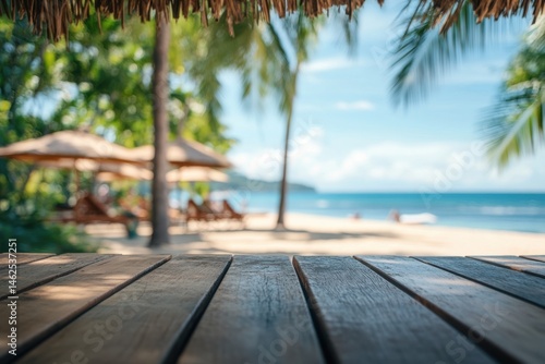 Blurred beach view from under a thatched roof with wooden foreground