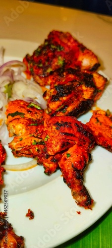 a plate of Tandoori Chicken, a popular Indian dish. The chicken pieces are marinated in a mixture of yogurt and spices, giving them a deep red or orange color, and then cooked in a tandoor 