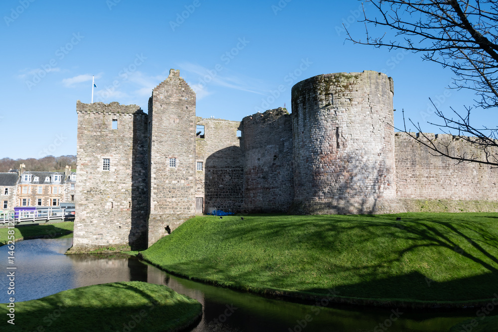Rothesay Castle ruin and moat on the Scottish island of Bute with stone circular plan towers and curtain walls on sunny summer blue sky day Rothesay Castle ruin and moat on the Scottish island of Bute with stone circular plan towers and curtain walls on sunny summer blue sky day