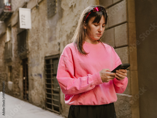 Obraz na płótnie Female athlete walking and typing on the phone she holds in front of her, on the street w salonie