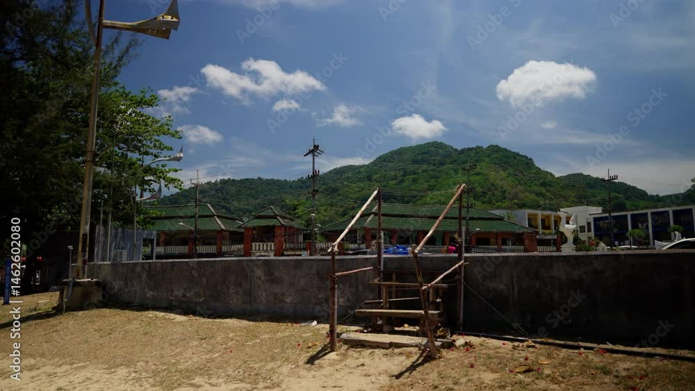 Wooden stairs stand on a sandy beach, a lush green hill rises in the background under a vibrant blue sky dotted with white clouds in thailand Wooden stairs stand on a sandy beach, a lush green hill rises in the background under a vibrant blue sky dotted with white clouds in thailand