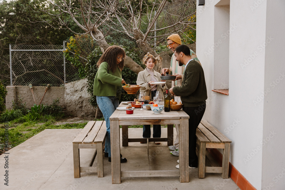 custom made wallpaper toronto digitalGroup of four friends standing at a table and putting food on plates, outdoors