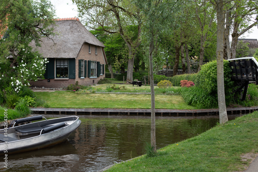 Obraz premium Giethoorn, Netherlands – A picturesque village with canals and rustic thatched-roof houses in a scenic farm area on a warm spring day in Europe.