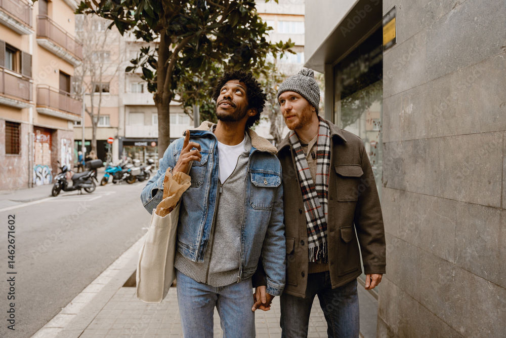 Naklejka premium A man walks and points up while holding the hand of a man walking next to him, on the street