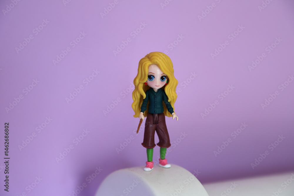Naklejka premium Toy figure of the character Luna Lovegood from Harry Potter. Collectible toy. Pink background. Isolated.