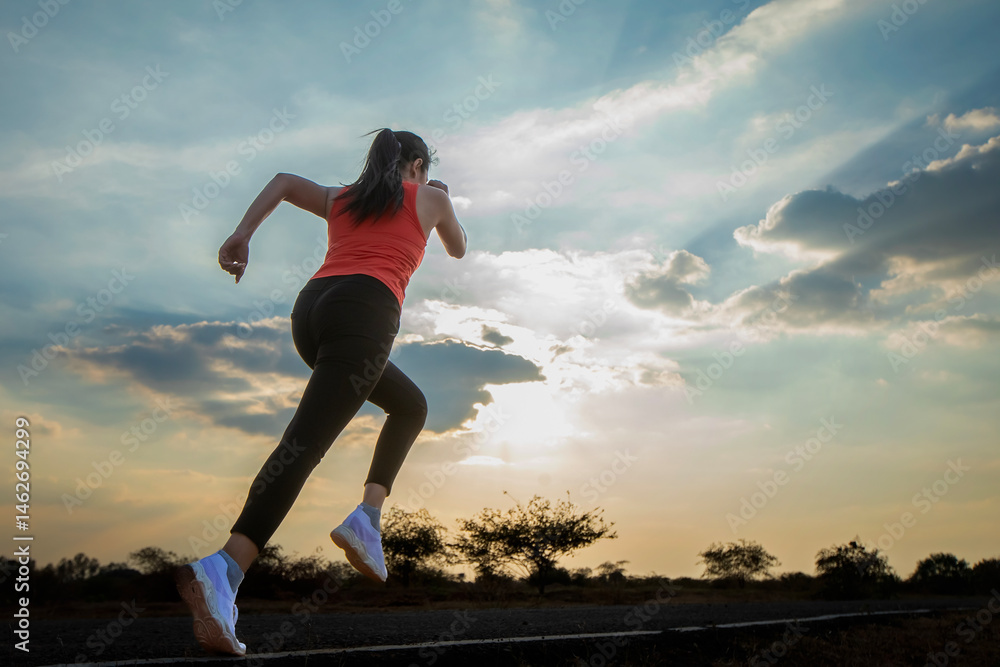 Fototapeta premium Silhouette of a beautiful young woman running against a colorful sky. Silhouette of a beautiful young woman running against a sunset background.