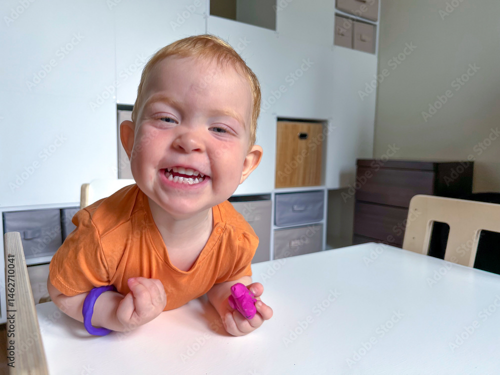 A little red-haired boy is joyful and happy playing at a table with plasticine. Early development of children at home