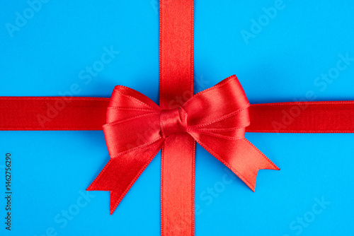 Obraz na płótnie Red ribbon and bow on blue background w salonie