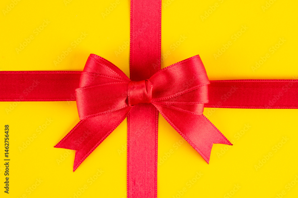 Red ribbon and bow on yellow background