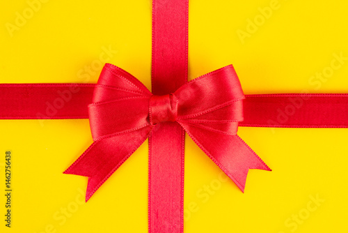 Obraz na płótnie Red ribbon and bow on yellow background w salonie
