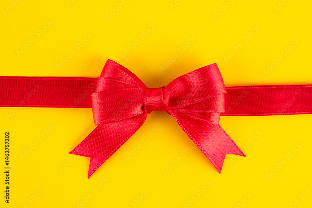 Red ribbon and bow on yellow background