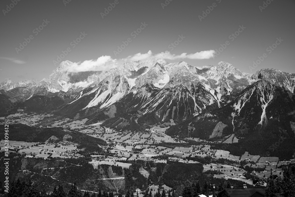Obraz premium Mountains rise majestically in the background, showcasing the Dachstein range from the vantage point of Planai. The lush valleys below contrast beautifully with the rugged peaks.
