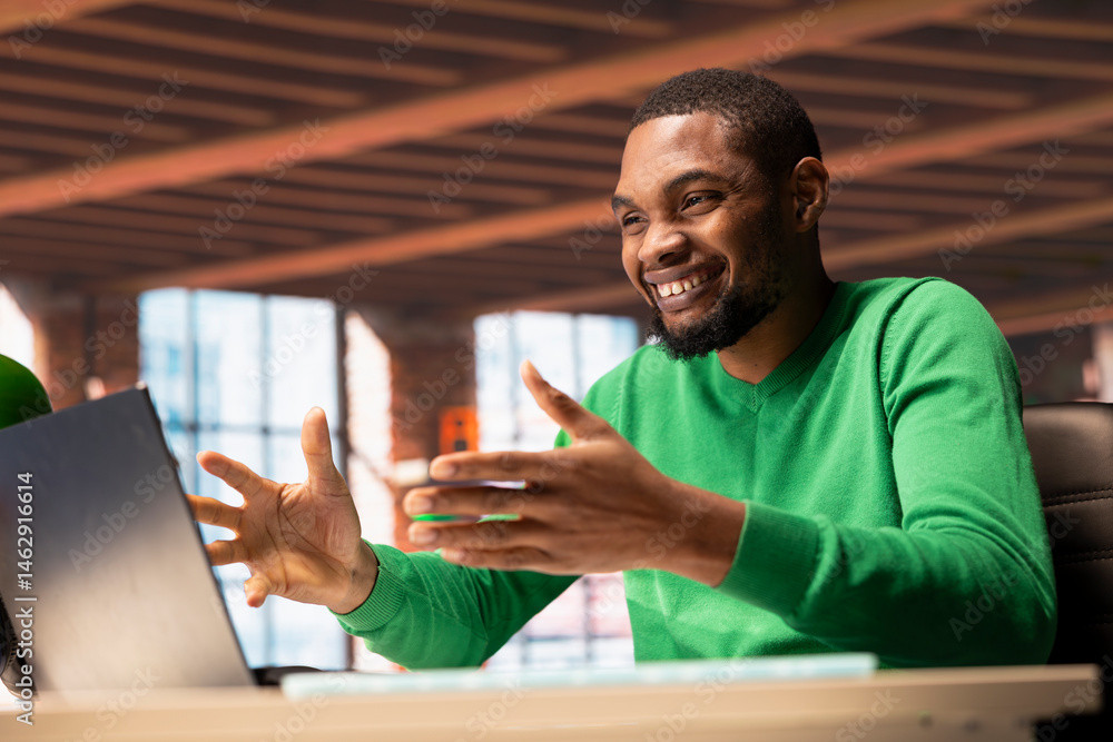 Happy man reading good news on laptop screen at home and cheering. Delighted african american person celebrating after reading positive information on notebook display in apartment
