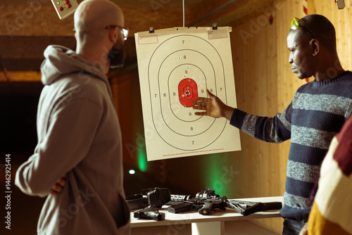 Obraz na płótnie Shooting range safety professional ensuring clients are operating rifles safely. Firing range gallery employee discussing rules with customers before allowing them to shoot semiautomatic weapons w salonie