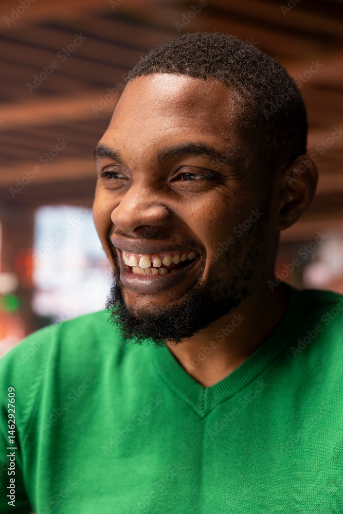 Portrait of jolly man at home looking upwards, feeling happy and grateful in life. Lively radiant african american person in apartment pleased with himself, feeling blessed