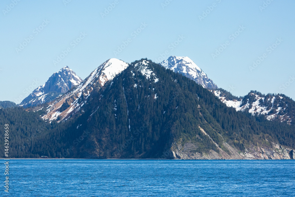 Obraz premium Snow capped mountains rise dramatically on the Kenai Peninsula, off the Alaskan coast.