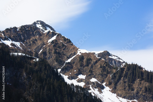 Snow capped mountains rise dramatically on the Kenai Peninsula, off the Alaskan coast.