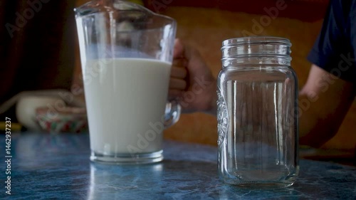 man's hand serving delicious fresh milk in a tumbler
