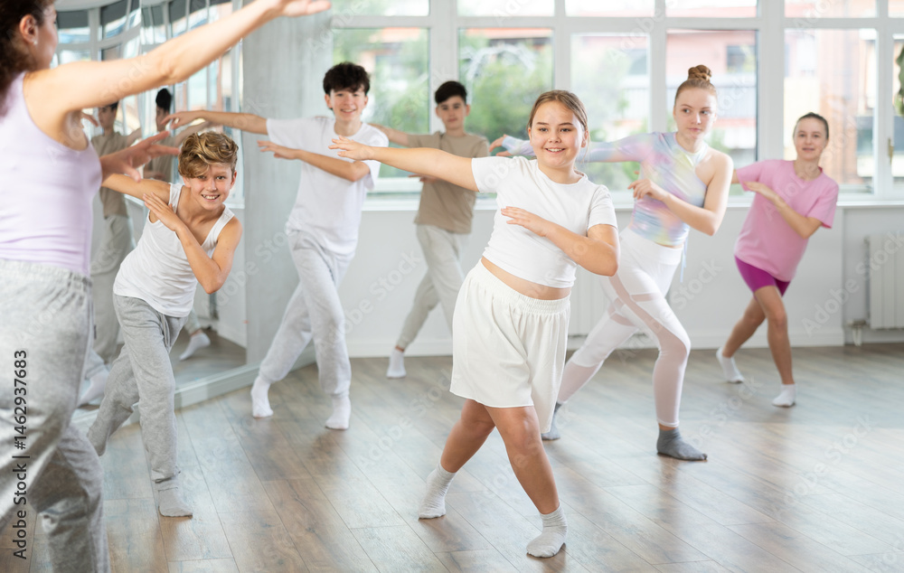 Naklejka premium Young girls and boys repeat the movements of dance teacher, training in a spacious studio