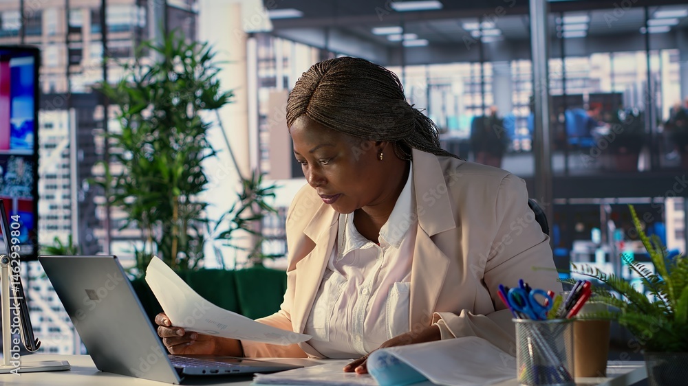 African american woman entrepreneur uses her leadership skills to navigate challenges in the corporate world, multitasking and working on strategic planning to achieve business success. Camera A.