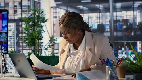 Obraz na płótnie African american woman entrepreneur uses her leadership skills to navigate challenges in the corporate world, multitasking and working on strategic planning to achieve business success. Camera A. w salonie