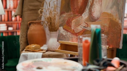 Empty art and craft workshop with a rustic beautiful painting on canvas, creative work with watercolor paint in a modern contemporary atelier. Artistic masterpiece with paint tubes and tools.