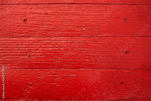 Closeup of red painted rustic wooden surface of an old ship  showing horizontal planks with natural wood grain and weathered texture. 
