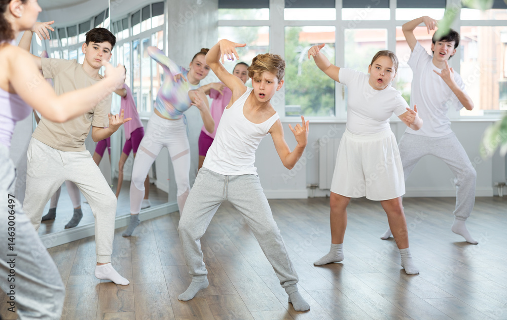 Naklejka premium Young girls and boys repeat the movements of dance teacher, training in a spacious studio