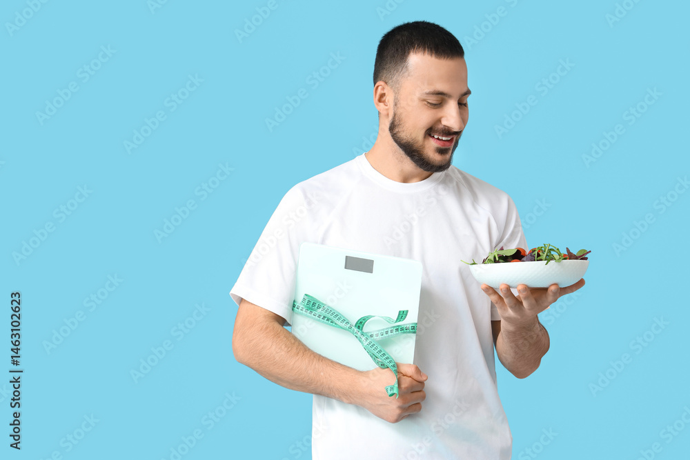 Sporty young man with scales, measuring tape and fresh vegetables on blue background. Healthy food concept Sporty young man with scales, measuring tape and fresh vegetables on blue background. Healthy food concept