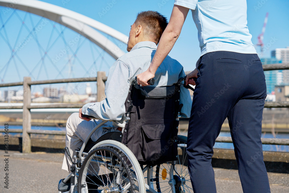 Obraz premium 介護士が押す車椅子に乗るシニア男性