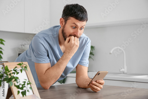 Surprised young man using m...