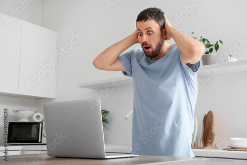 Shocked young man using lap...