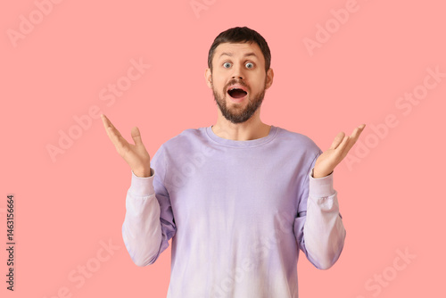 Surprised young man on pink...