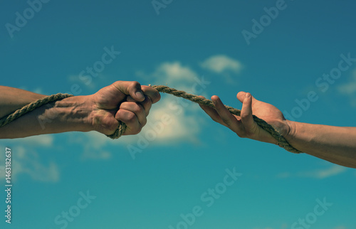 Obraz na płótnie Conflict or tug. Two hands, helping hand, arm, friendship. Rope, cord. Hand holding a rope, climbing rope, strength and determination. Rescue, help, helping gesture hands. Helping hand support concept w salonie