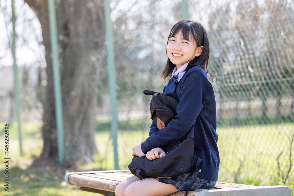 グラウンドのベンチに座る女子学生