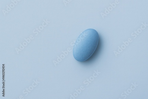 A single blue pill resting on a soft blue background, showcasing a simple and clean pharmaceutical tablet design