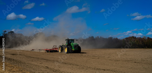 Tractor ploughing soil on field. Farming on soil ground. Tractor on rural farmland. Agricultural machine or tractor working on soil. Tractor plowing ground for cultivation. Farm soil ground.