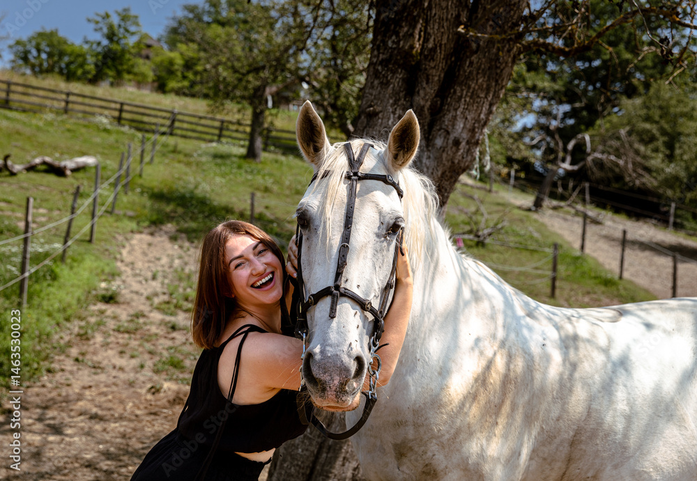 Obraz premium Smiling young caucasian female embraces white horse outdoors