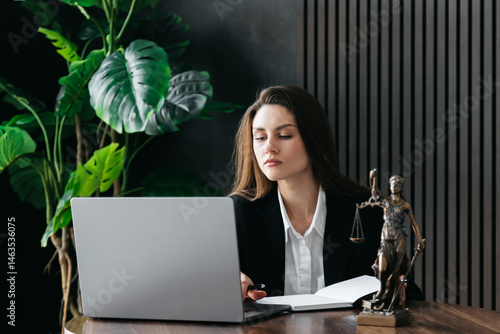 Canvas Print A young female lawyer studies new laws and makes edits at a laptop in a modern office