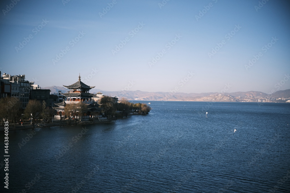 Fototapeta premium A scenic view of Dali city where urban structures meet the calm waters of Erhai Lake, located in Yunnan Province, China. 