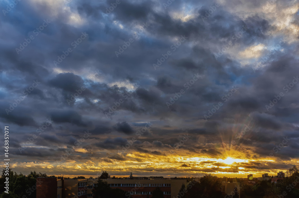 Obraz premium Cloudy orange blue sunset over dark silhouettes of city building